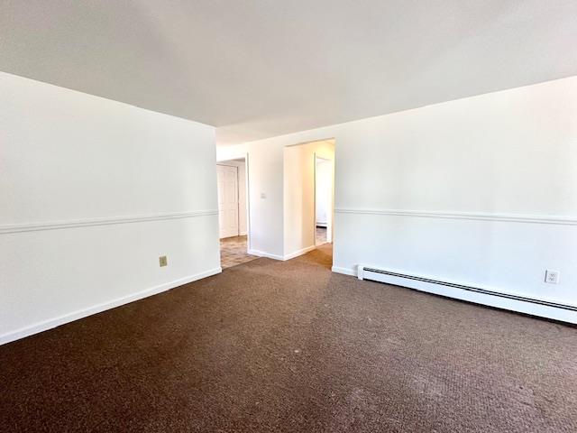 unfurnished room featuring baseboard heating and carpet floors