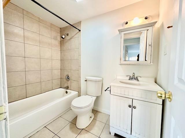 full bathroom featuring vanity, tiled shower / bath, tile patterned floors, and toilet