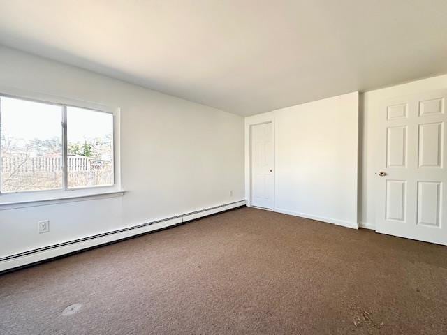 unfurnished bedroom with dark carpet and a baseboard radiator