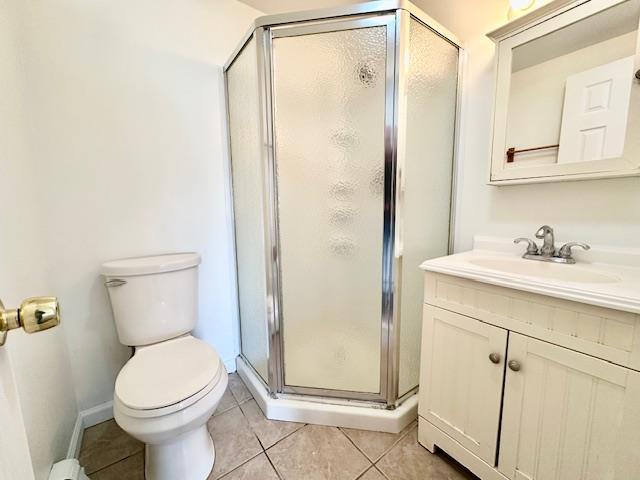 bathroom featuring tile patterned flooring, vanity, an enclosed shower, and toilet