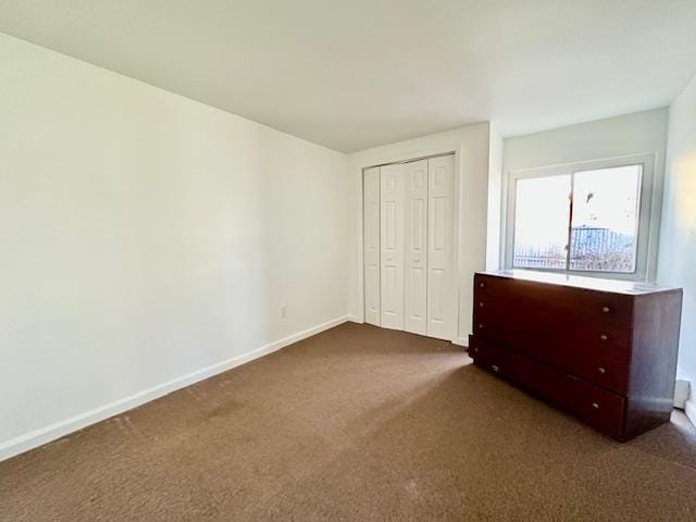 unfurnished bedroom featuring dark carpet and a closet