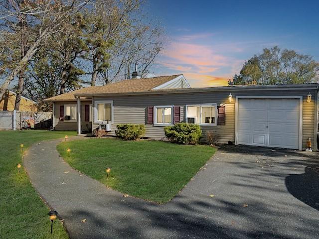 ranch-style house featuring a garage and a yard