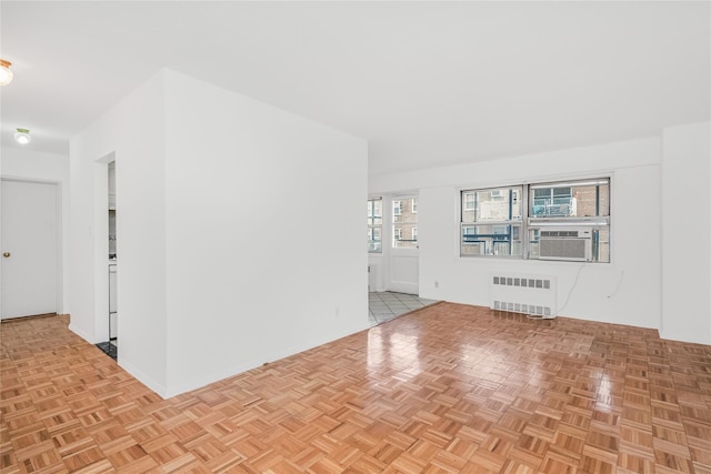 unfurnished living room with cooling unit, radiator heating unit, and light parquet floors