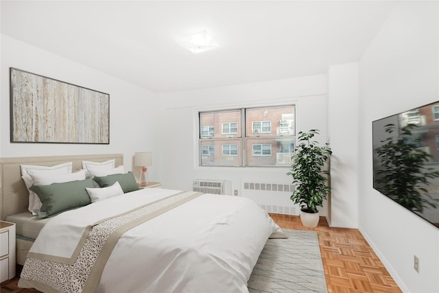 bedroom featuring radiator, a wall unit AC, and light parquet flooring