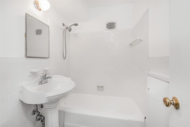 bathroom with tile walls and tiled shower / bath