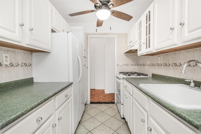 kitchen featuring sink, white appliances, light tile patterned floors, ceiling fan, and white cabinetry