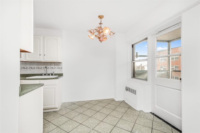 unfurnished dining area with sink, radiator heating unit, a notable chandelier, and light tile patterned floors