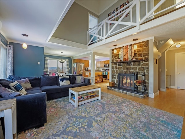 living room featuring ornamental molding, a stone fireplace, hardwood / wood-style floors, and a high ceiling