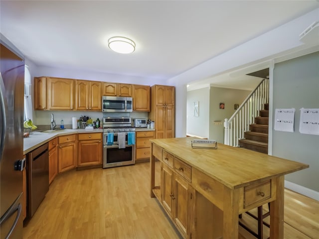 kitchen featuring stainless steel appliances, a kitchen island, sink, and light hardwood / wood-style floors