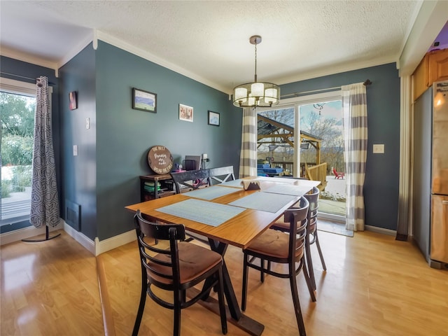 dining space featuring an inviting chandelier, crown molding, light hardwood / wood-style floors, and a textured ceiling