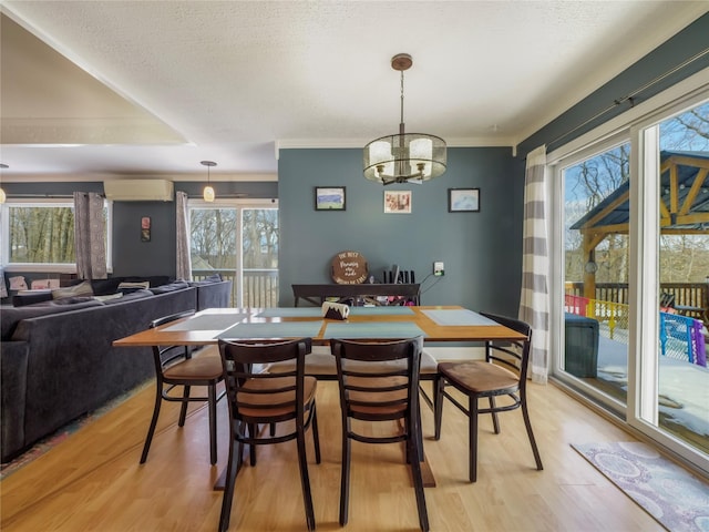 dining area featuring a wall mounted air conditioner, light hardwood / wood-style flooring, and a textured ceiling