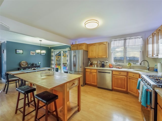 kitchen with a kitchen island, appliances with stainless steel finishes, pendant lighting, sink, and a breakfast bar area