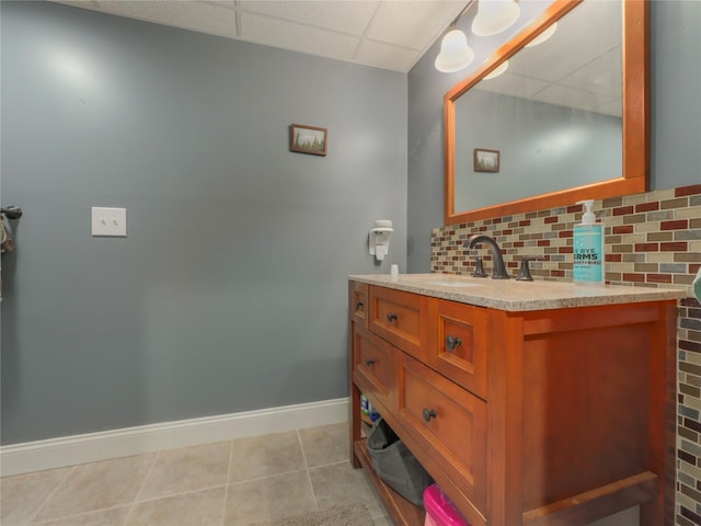 bathroom with vanity, a drop ceiling, backsplash, and tile patterned floors