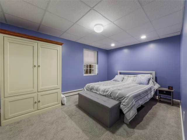 carpeted bedroom featuring a drop ceiling and a baseboard radiator