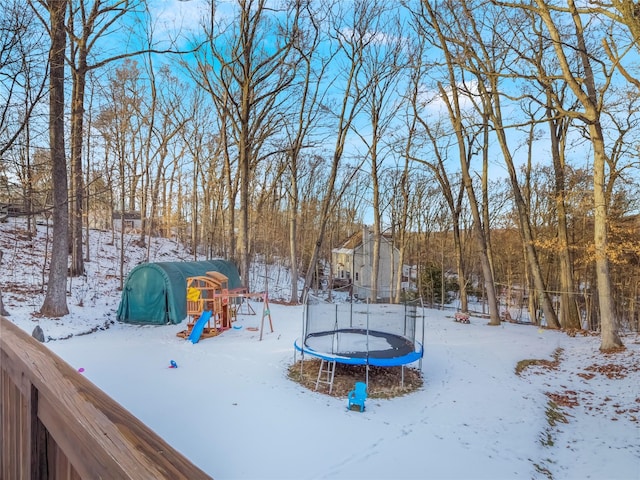 snowy yard with a playground and a trampoline