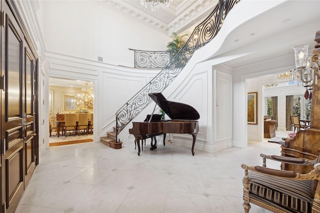 entryway featuring crown molding, a towering ceiling, and an inviting chandelier