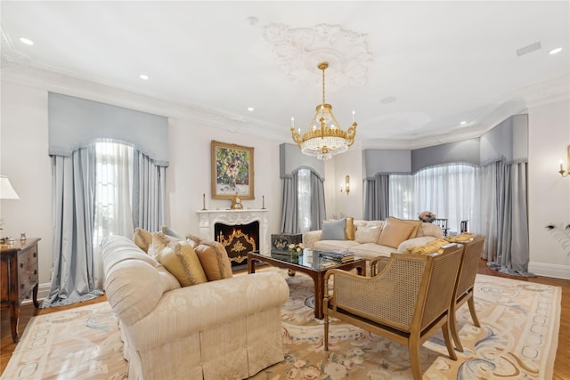 living room featuring ornamental molding, a chandelier, a high end fireplace, and light hardwood / wood-style floors