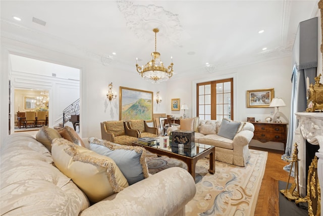 living room with french doors, an inviting chandelier, ornamental molding, a fireplace, and light parquet floors