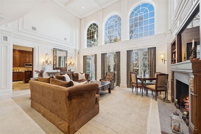 tiled living room with beamed ceiling, ornamental molding, coffered ceiling, and a towering ceiling