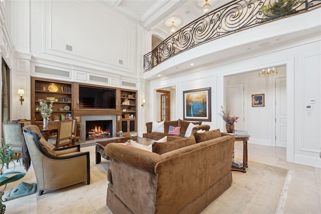 living room featuring built in shelves, ornamental molding, and a high ceiling