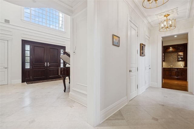 entryway featuring ornamental molding, a towering ceiling, light tile patterned floors, and an inviting chandelier