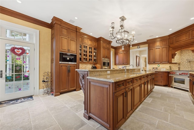 kitchen featuring sink, decorative light fixtures, a large island with sink, appliances with stainless steel finishes, and backsplash