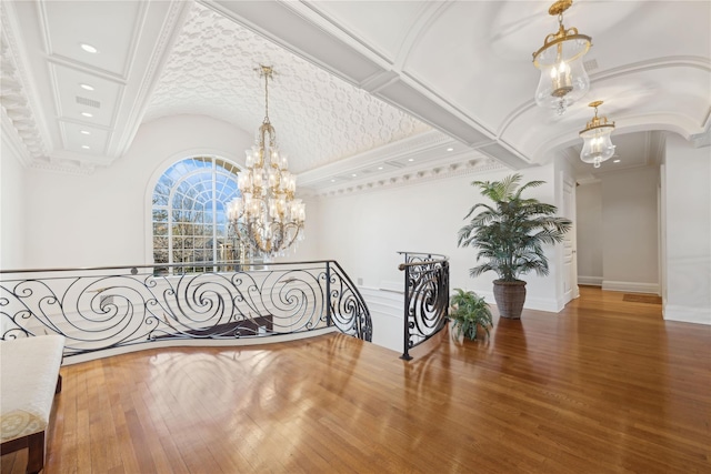 hall featuring lofted ceiling, crown molding, wood-type flooring, and a chandelier