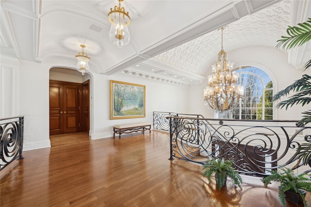 hall with hardwood / wood-style flooring, vaulted ceiling, and a notable chandelier