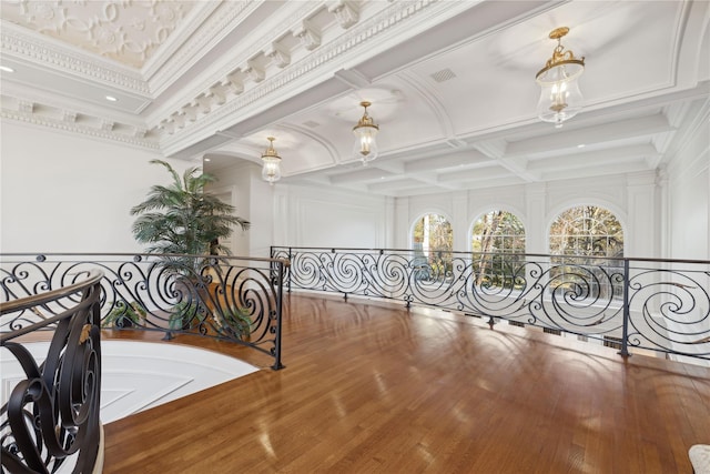 corridor with crown molding, coffered ceiling, hardwood / wood-style floors, and beam ceiling