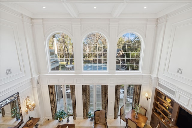 interior space featuring beamed ceiling, ornamental molding, coffered ceiling, and a wealth of natural light