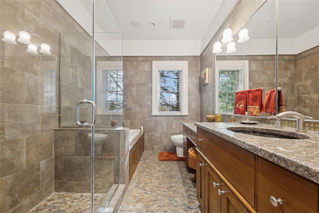 bathroom with tile walls, tile patterned flooring, vanity, toilet, and a shower with door