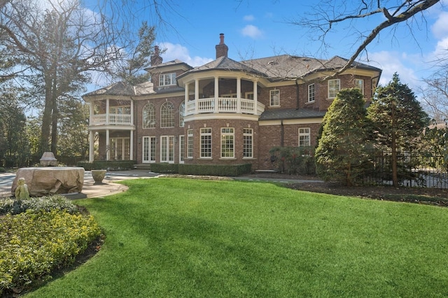 rear view of property with a balcony, a sunroom, and a lawn