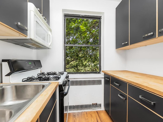 kitchen with wood counters, radiator, black range with gas stovetop, and plenty of natural light