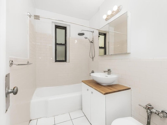 bathroom with tile walls, vanity, tile patterned flooring, and tiled shower / bath combo