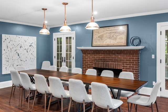 dining area featuring a brick fireplace, crown molding, dark wood-type flooring, and french doors