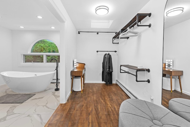 bathroom with a skylight, a baseboard radiator, and a tub to relax in