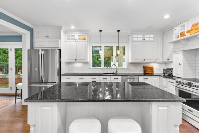 kitchen with appliances with stainless steel finishes, a center island, dark stone countertops, and white cabinets