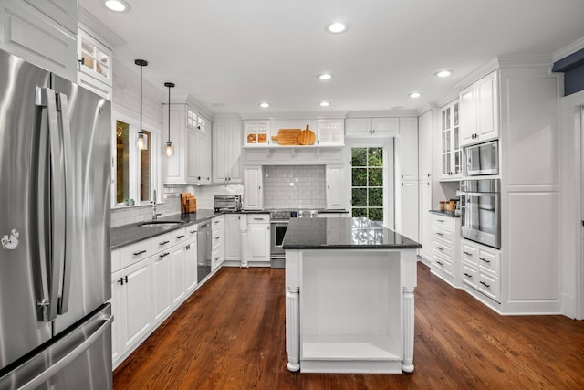 kitchen with a kitchen island, appliances with stainless steel finishes, sink, white cabinets, and hanging light fixtures