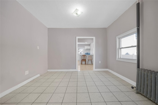 tiled spare room featuring radiator