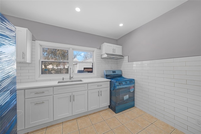 kitchen featuring white cabinetry, sink, tile walls, stainless steel range with electric cooktop, and light tile patterned floors