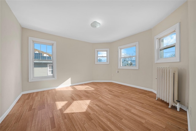 unfurnished room featuring radiator heating unit and light hardwood / wood-style floors