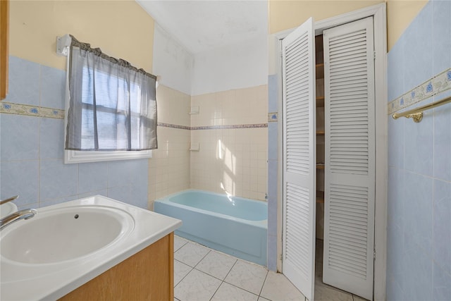 bathroom with vanity, a bath, tile patterned flooring, and tile walls