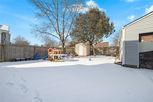 yard layered in snow with a playground and a storage shed