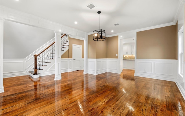 spare room with decorative columns, ornamental molding, and hardwood / wood-style flooring