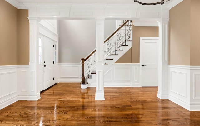 foyer entrance featuring hardwood / wood-style flooring, ornamental molding, and ornate columns