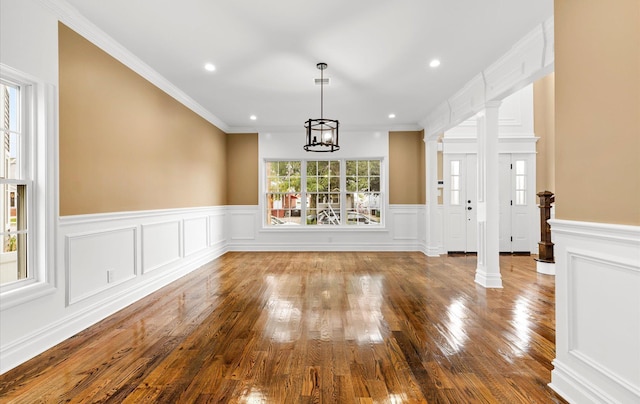 unfurnished living room featuring decorative columns, ornamental molding, hardwood / wood-style floors, and a wealth of natural light