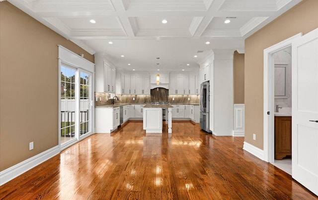 kitchen featuring coffered ceiling, white cabinetry, tasteful backsplash, a center island, and stainless steel refrigerator