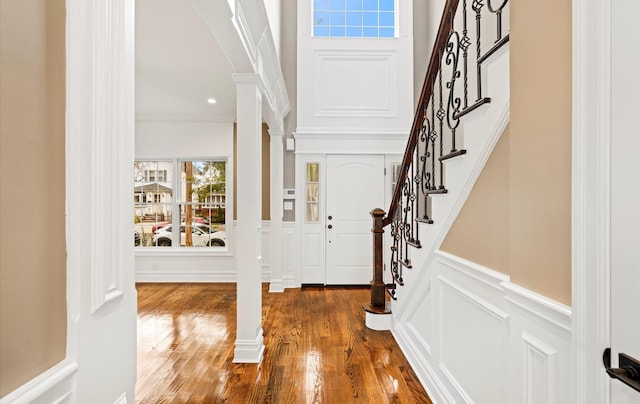 foyer entrance featuring crown molding, decorative columns, and dark hardwood / wood-style floors