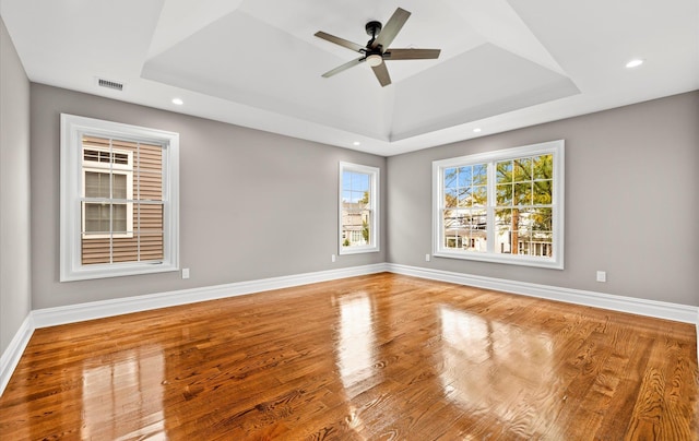 spare room featuring a tray ceiling, wood-type flooring, and ceiling fan