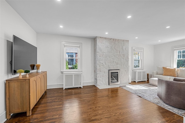 living room with a stone fireplace, radiator heating unit, and dark hardwood / wood-style flooring